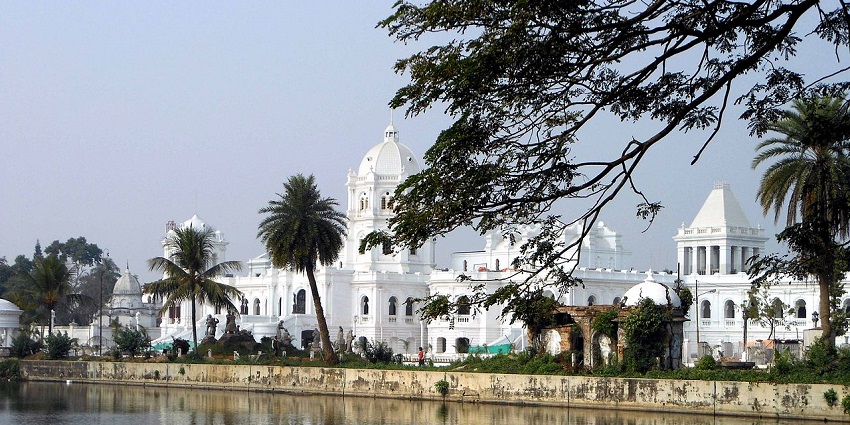 A scenic view of Tripura State Museum surrounded by lush greenery and azure waters.