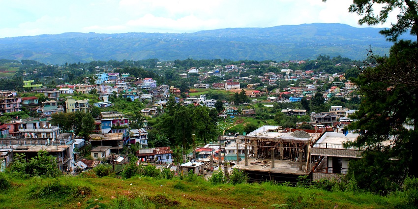 A picture of a hill station taken from another hill showing a town