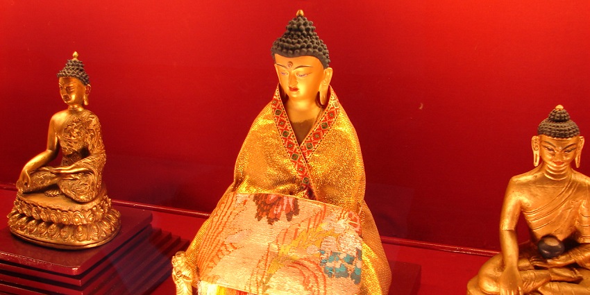 A mesmerising view of three gold statues of Lord Budhha covered in golden clothes.