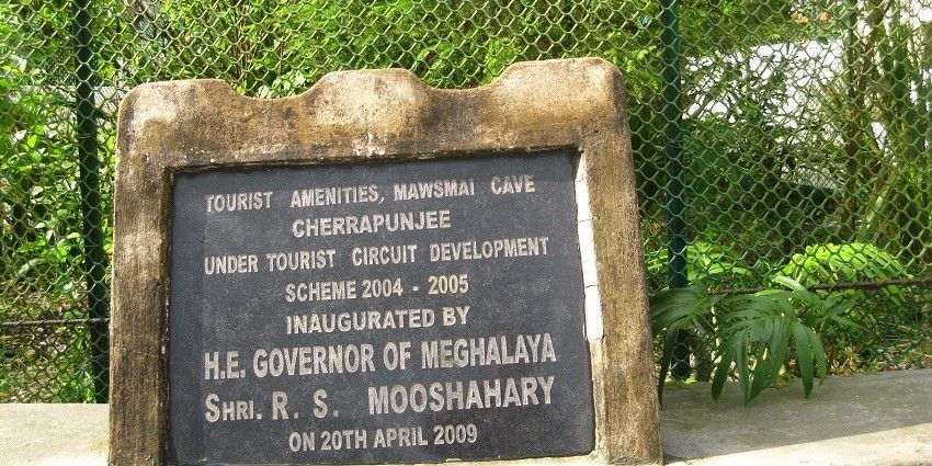 A picture of a cave system's entrance with details written on a marble board
