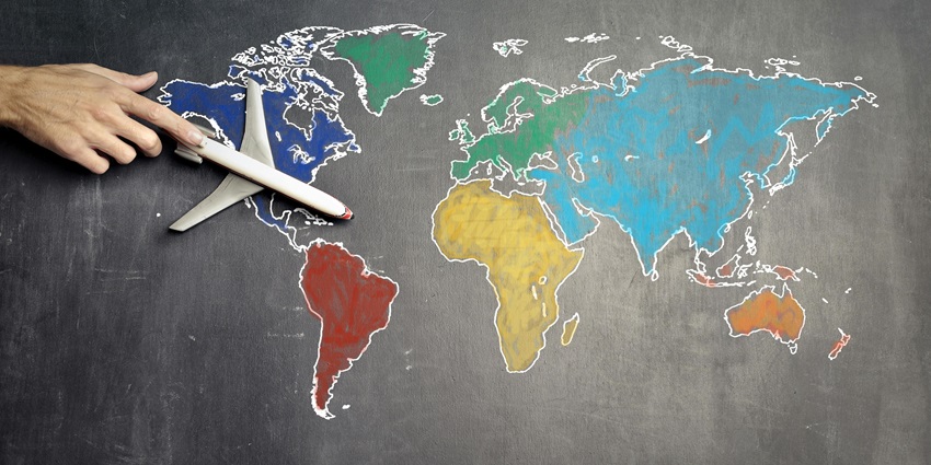 A view of a colourful map drawn on a blackboard with a white miniature aeroplane.