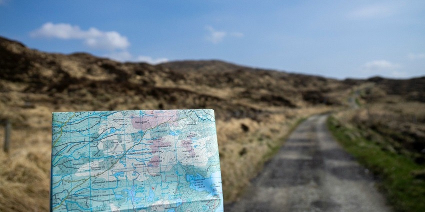 A selective focused view of a map with mountains and lush greenery in the background.