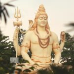 Lord Shiva's statue stands tall amidst vibrant trees, creating a tranquil atmosphere.