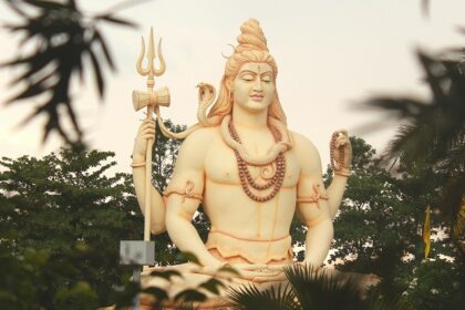 Lord Shiva's statue stands tall amidst vibrant trees, creating a tranquil atmosphere.