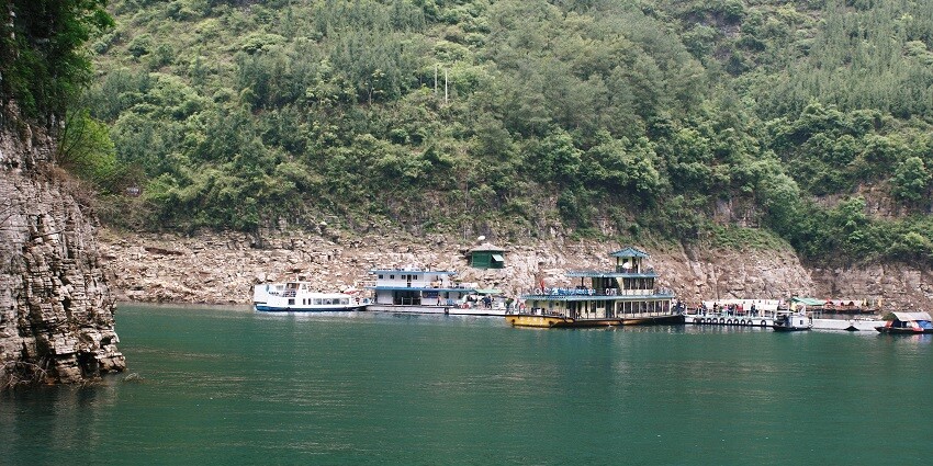 Tranquil river scene with lush green vegetation and a wooden boat on the calm water.