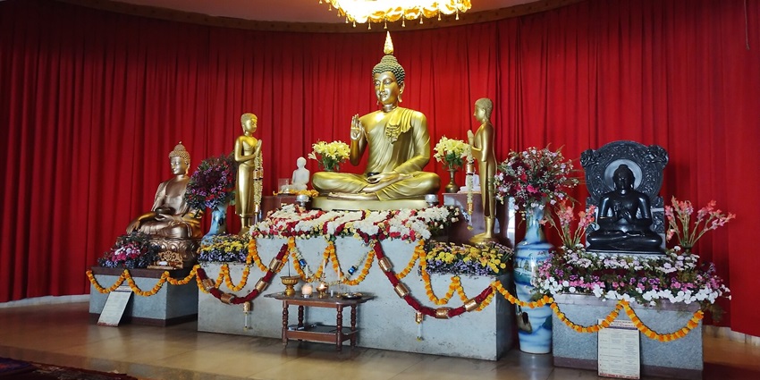 A picture of a Buddha temple in Delhi from the inside with a golden sculpture of Lord Buddha placed on a pedestial