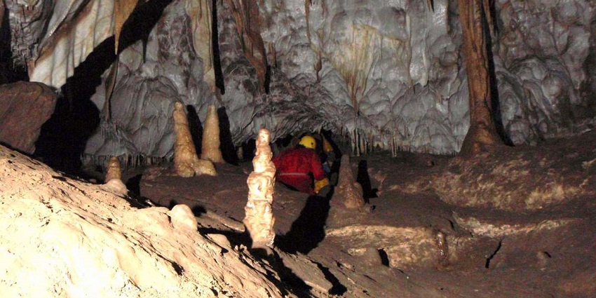 Calcite formations in Gavel Pot, displaying natural beauty within a dark cave chamber.