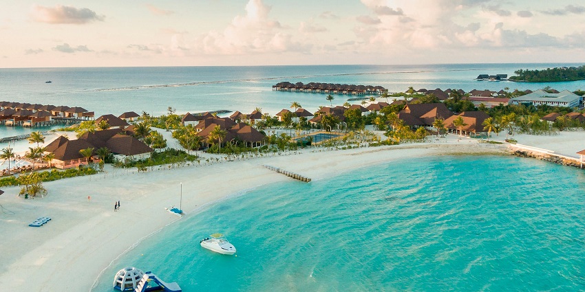 A stunning view of a body of water in the Maldives with houses and green trees around.
