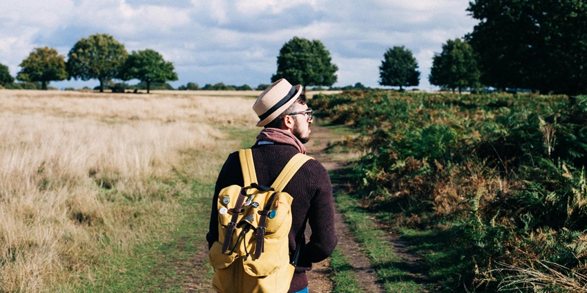 Man with a Backpack Strolling Across a Field - trip for trip to Tripureswari Temple