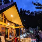 A breathtaking view of a brown hut in Manali with a man standing in front of it.