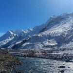 A breathtaking view of enormous snow-capped mountains with a sparkling water body.