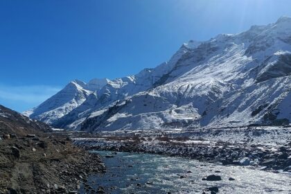 A breathtaking view of enormous snow-capped mountains with a sparkling water body.