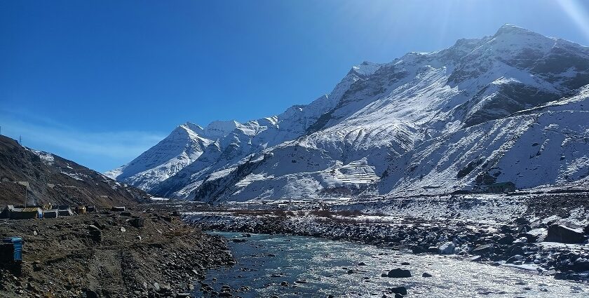 A breathtaking view of enormous snow-capped mountains with a sparkling water body.