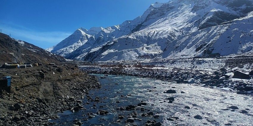 Image of bright sunlight illuminating snowy mountain peaks under a clear blue sky.