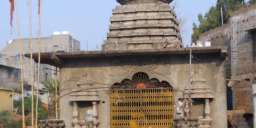 A frontal view of a temple near the Chellarkovil Waterfalls, with flags on the rooftop