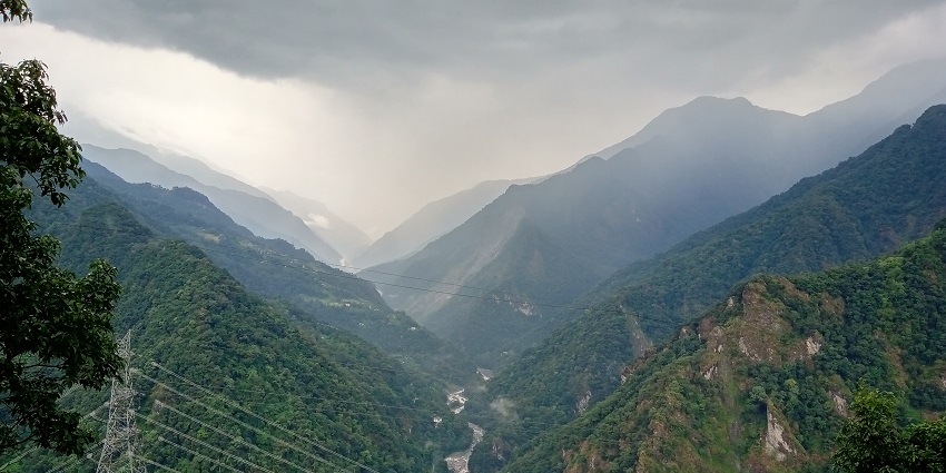 A narrow river flowing through the rocky terrains of lush green valleys of Mangan.