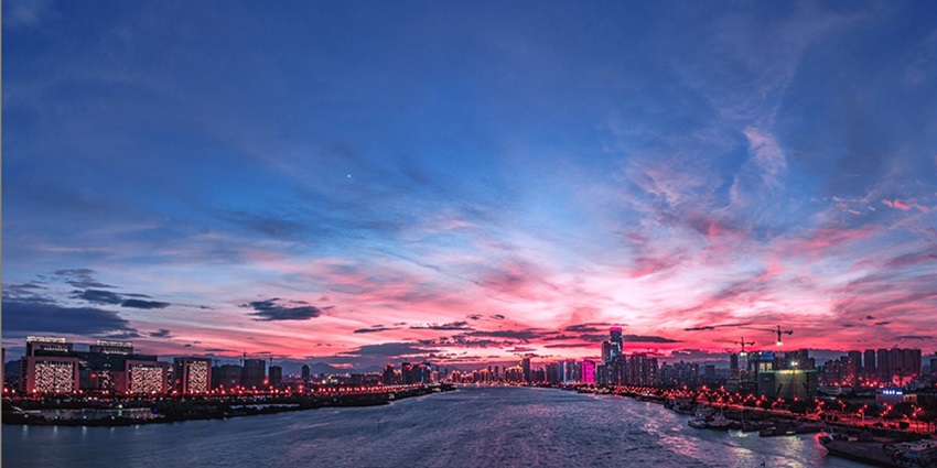 Fuzhou cityscape with tall buildings and city lights illuminating the skyline at dusk.