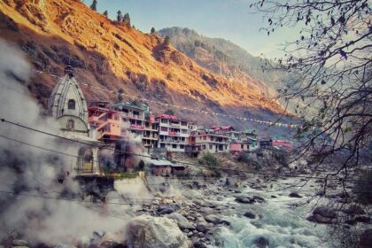 A breathtaking view of a river flowing through a Manikaran with houses on the side.