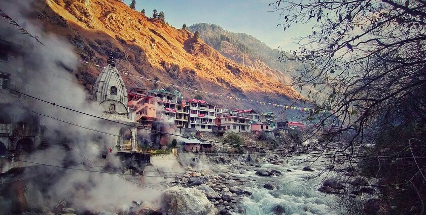 A breathtaking view of a river flowing through a Manikaran with houses on the side.