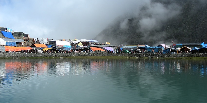 A captivating view of the Manimahesh Lake with mist and mountains in the background.