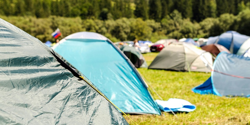 A breathtaking view of blue and grey dome tents surrounded by trees during the day.