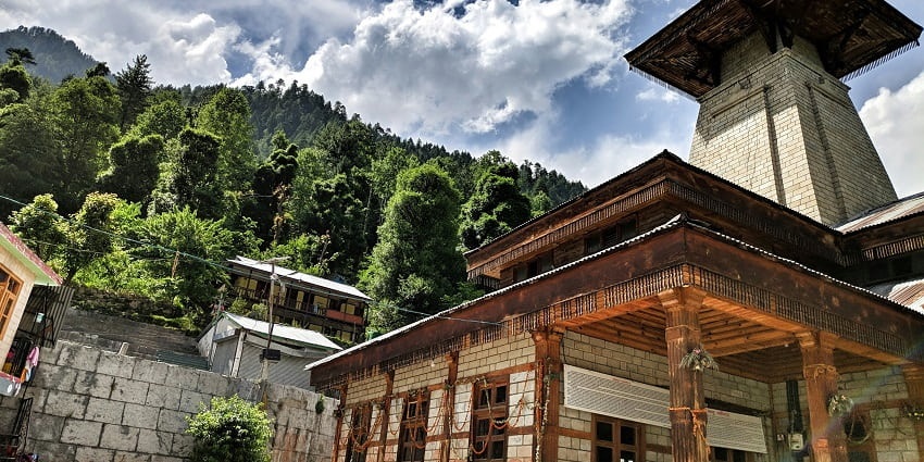 A breathtaking view of Manu Temple during the day under dense clouds surrounded by trees.