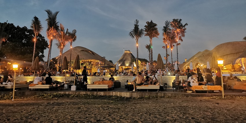 A picture of a beachside party with bonfire and people enjoying the cosy nightlife