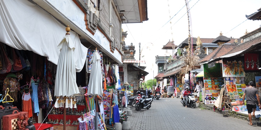 A picture of a bustling market in Ubud with numerous shops visible across the street