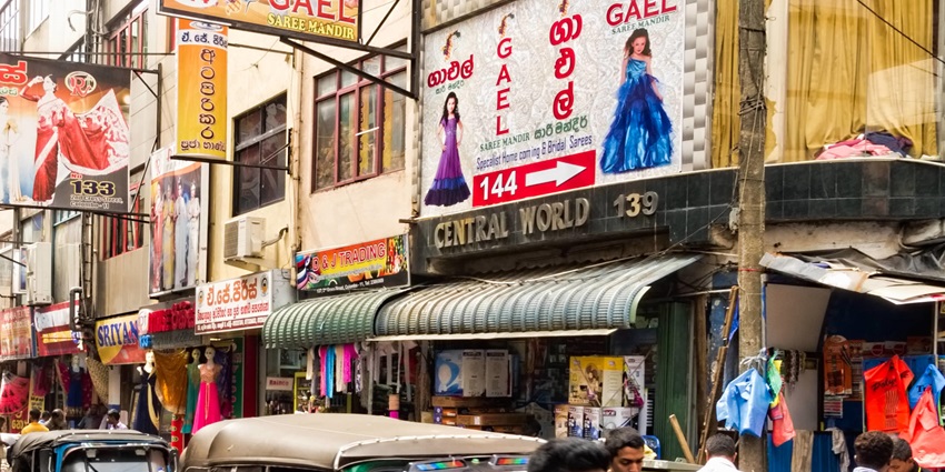 A picture of a bustling market in Colombo with numerous shops visible around the street