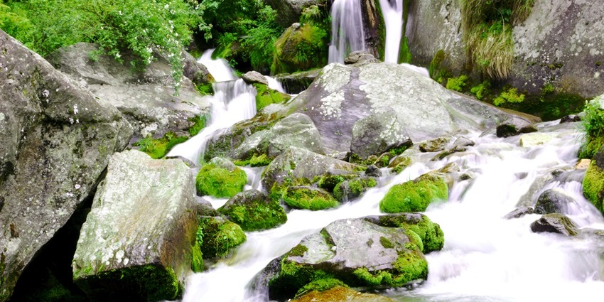 A stunning view of the idyllic Jogini Waterfalls surrounded by lush green vegetation.
