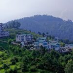 A breathtaking view of a lush green valley with colourful houses during the daytime.