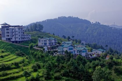 A breathtaking view of a lush green valley with colourful houses during the daytime.