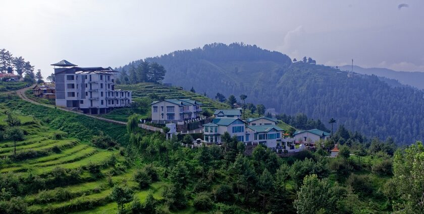 A breathtaking view of a lush green valley with colourful houses during the daytime.