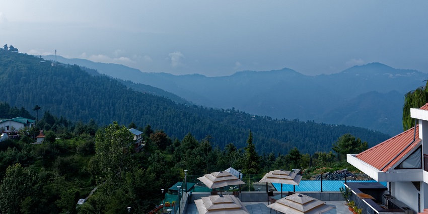 Beautiful landscape of Mashobra featuring green hills and vibrant trees against blue skies.