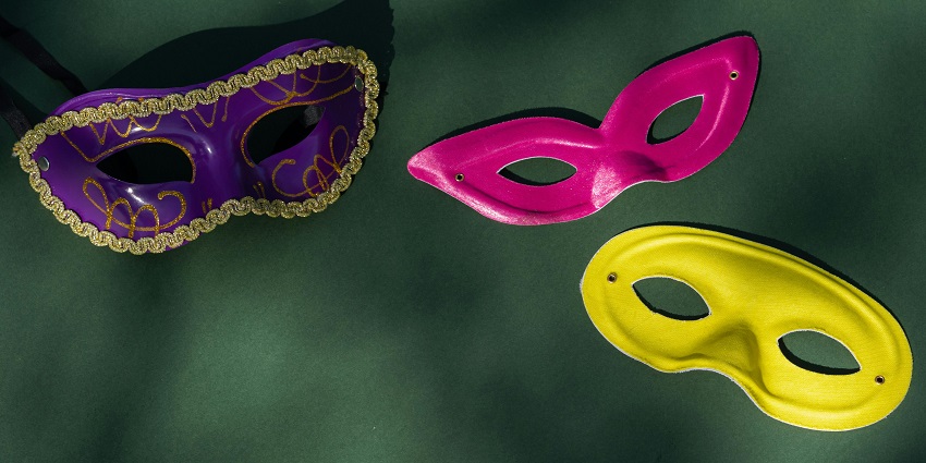 Colourful carnival mask in purple, pink, and yellow with intricate feather details.