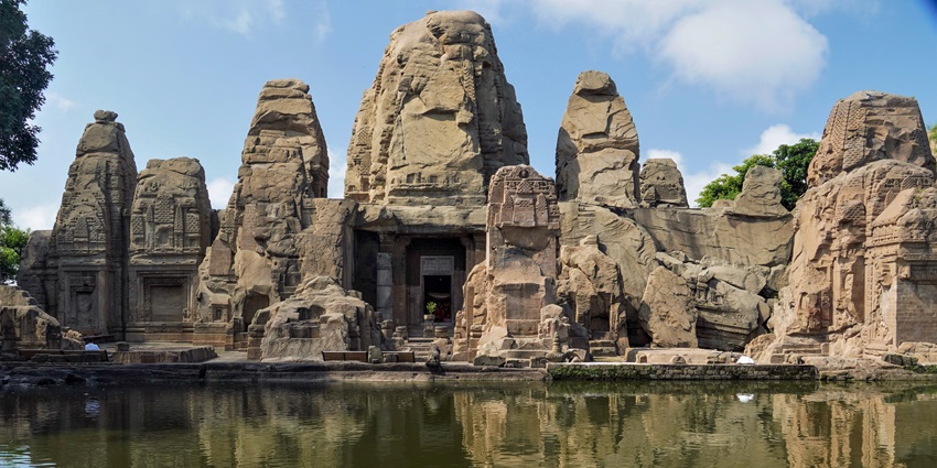 A picture of an ancient rock cut temple with its reflection falling in a pond in front