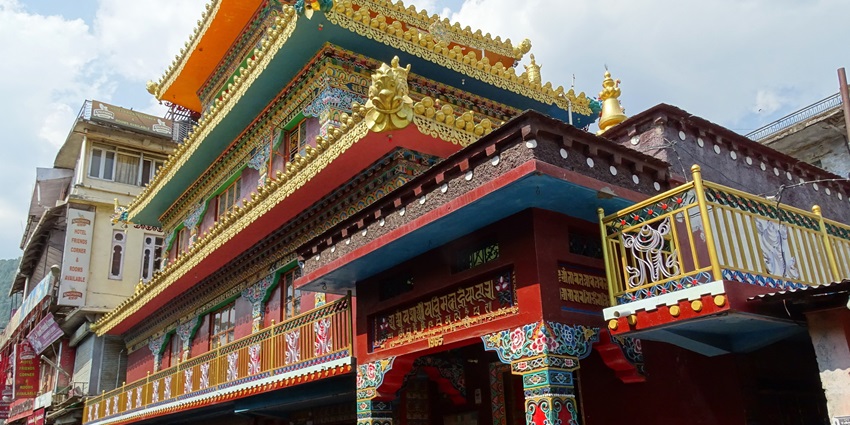 Main street view in McLeod Ganj with temple, shops, and people in a lively setting.