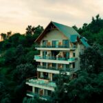 A breathtaking view of a house in Himachal surrounded by lush greenery during the daytime.