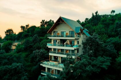 A breathtaking view of a house in Himachal surrounded by lush greenery during the daytime.