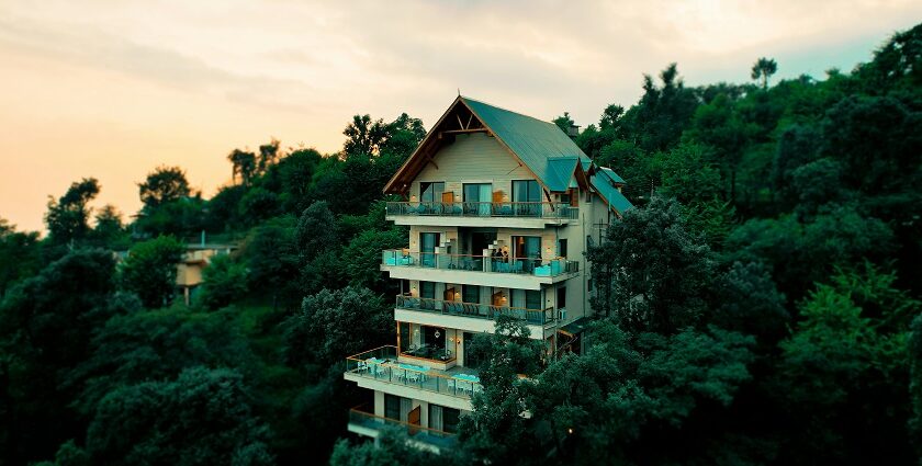 A breathtaking view of a house in Himachal surrounded by lush greenery during the daytime.