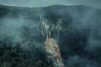 A mesmerising view of a waterfall in Meghalaya surrounded by lush greenery during the day.