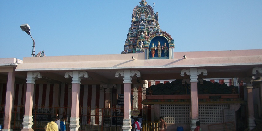 A frontal view of a temple with a tall Gopurama and sculptures of Hindu deities on its roof