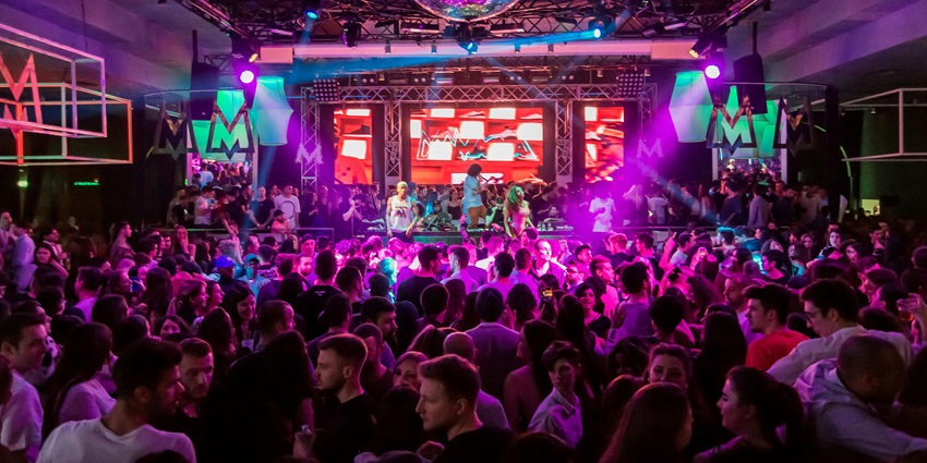 People inside a lively club with dim lighting and energetic atmosphere.