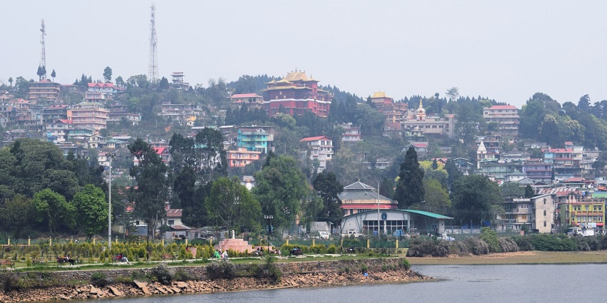 Scenic view of Mirik in West Bengal with pine trees, lake, and rolling green hills.