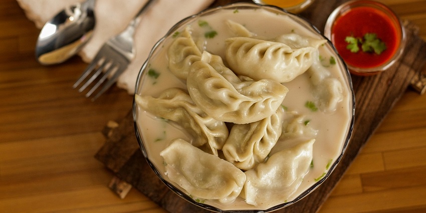 A plate of Momo, featuring spicy side chutney and gravy on the side, served in Shimla.