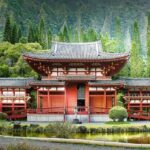 A scenic view of a religious house in hues of red and brown surrounded by lush greenery.