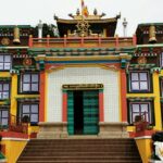 An amazing view of a yellow monastery with a white gate and a brown roof during the day.