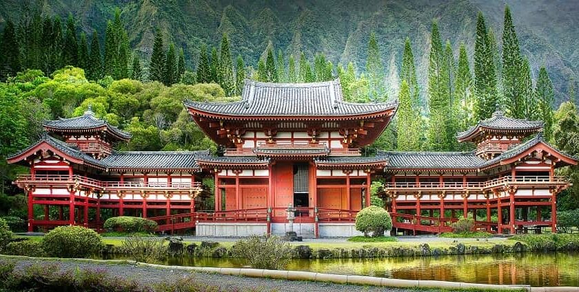 A scenic view of a religious house in hues of red and brown surrounded by lush greenery.