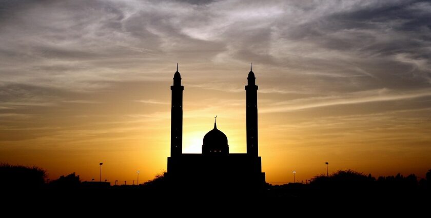 A silhouette of a mosque with a scenic backdrop of cloudy skies with a beautiful sunset.