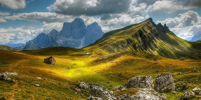 The panoramic wide shot of the mountains and the meadows during the evening time